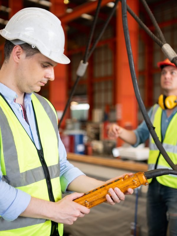 Two young engineers Testing and checking the operation of the over head crane in the factory.